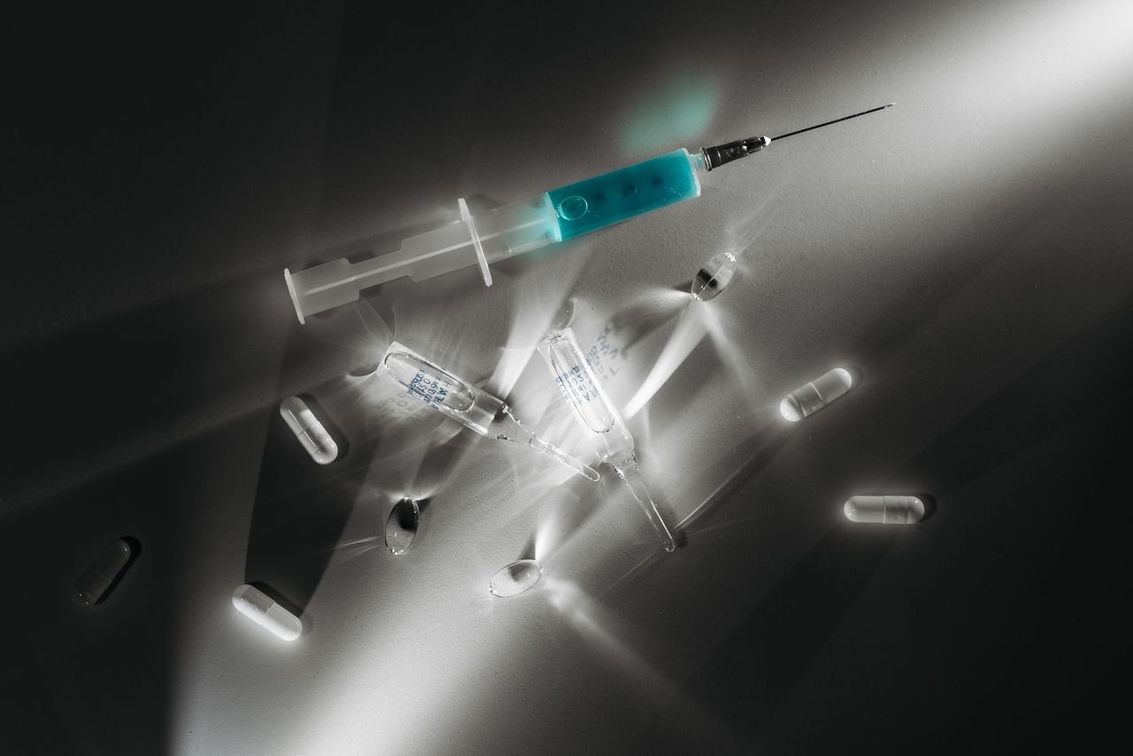 High contrast image of medical supplies, including a syringe and capsules, in a monochrome setting.